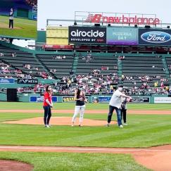 A view from the third base line at Fenway shows five people standing near the mound. One has thrown a ball that's on the way to the catcher.